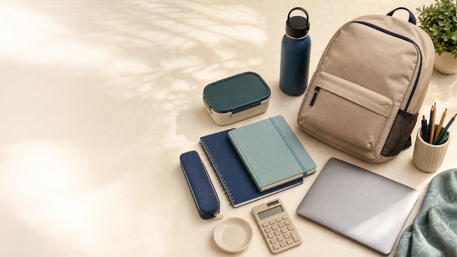 Back-to-school shopping checklist with a backpack, notebooks, reusable water bottle, lunch box and laptop on a warm study desk